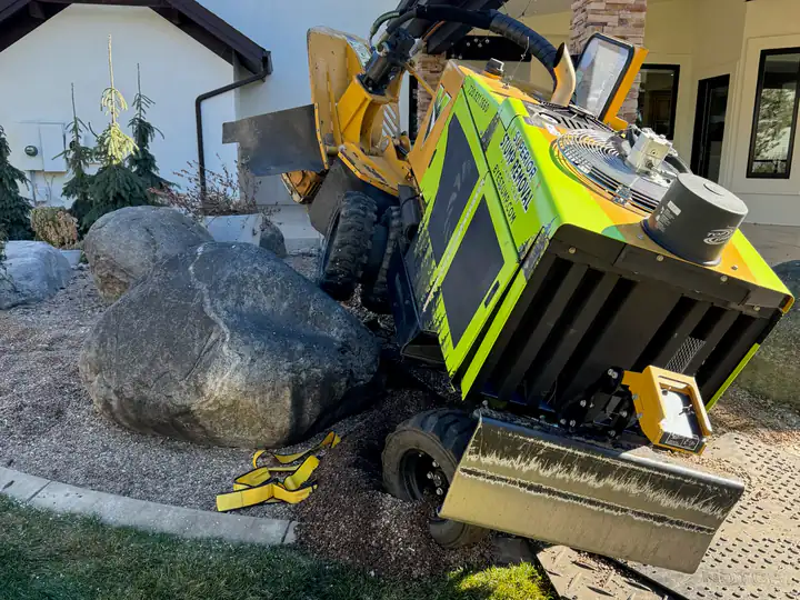 Stump grinding in Castle Rock, CO: stump grinder working a stump beside a house