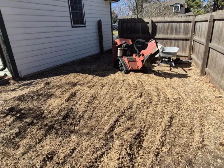 Stump grinding in Cherry Hills Village, CO: freshly ground stump area along a fence