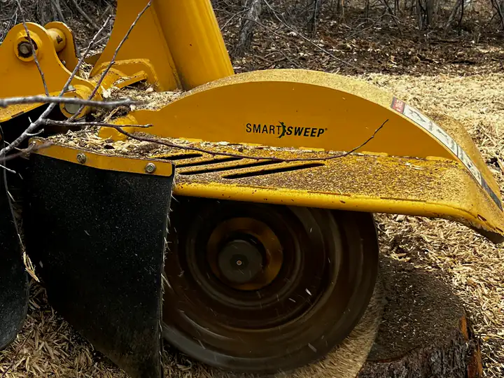 Stump grinding in Englewood, CO: stump grinder wheel chewing a stump below grade