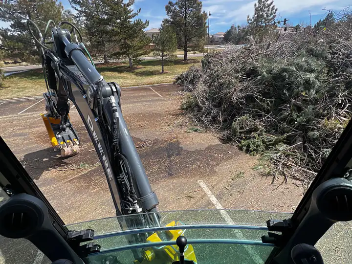 Land clearing in Parker, CO: excavator cab view on a clearing job